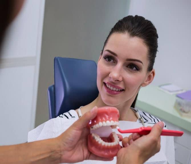Dentist Explaining Functionality Of Partial Dentures TO Female Patient
